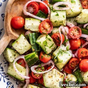 Refreshing Mediterranean Cucumber Salad with Feta and Mint 8 A wood spoon dipping into a bowl of mediterranean cucumber salad.