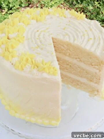 Lemon Buttermilk Cake, sliced, on a glass pedestal.