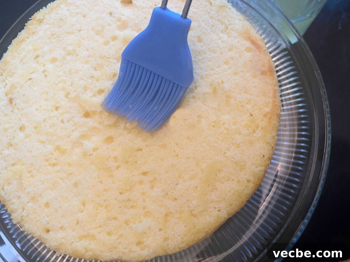 Lemonade Layer Cake Recipe with Bright Lemon Frosting 7 Brushing lemonade cake layer with lemonade, using a pastry brush.