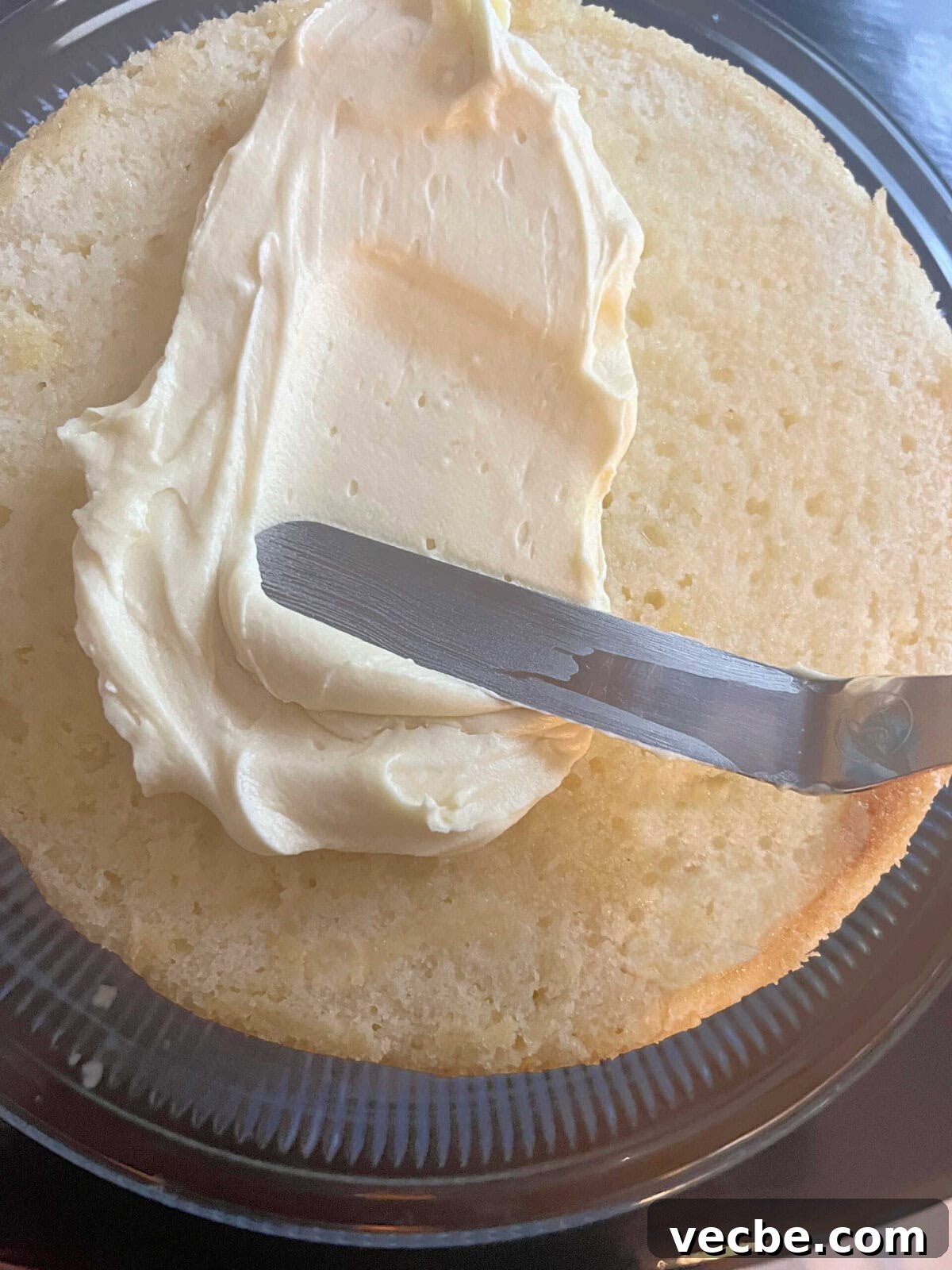 Lemonade Layer Cake Recipe with Bright Lemon Frosting 8 Applying lemon cream cheese frosting to the cake layer.