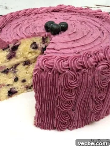 Lemon Blueberry Cake, sliced, on a cake pedestal.