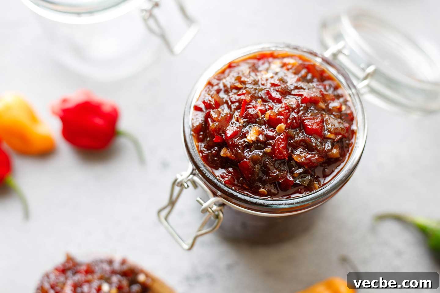 Homemade Sweet and Spicy Pepper Relish Recipe 9 Overhead of jelly jar filled with pepper relish, with a few hot peppers scattered nearby.