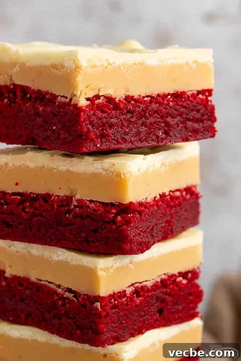 Red Velvet Millionaire Brownies Recipe with Caramel and Chocolate 7 A close up of 4 red velvet millionaire brownies in a stack set against a mottled light background.