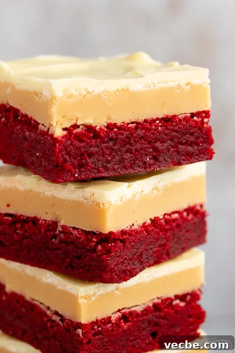 Red Velvet Millionaire Brownies Recipe with Caramel and Chocolate 10 A close up of 4 red velvet millionaire brownies in a stack set against a mottled light background.