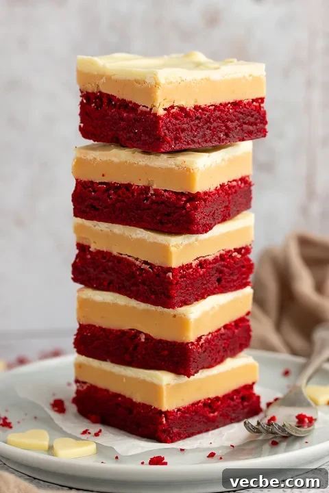Red Velvet Millionaire Brownies Recipe with Caramel and Chocolate 15 A stack of 5 red velvet millionaire brownies set on two stacked plates with a fork on the side.