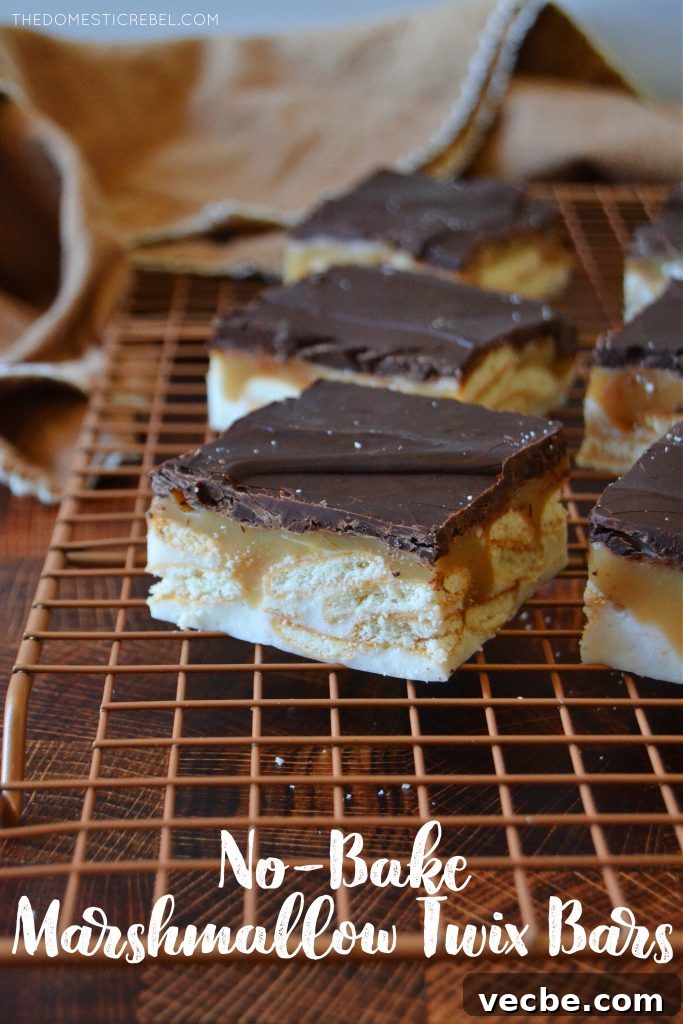 No-Bake Marshmallow Twix Bars Recipe 2 twix no-bake marshmallow bars on a gold wire rack with a towel