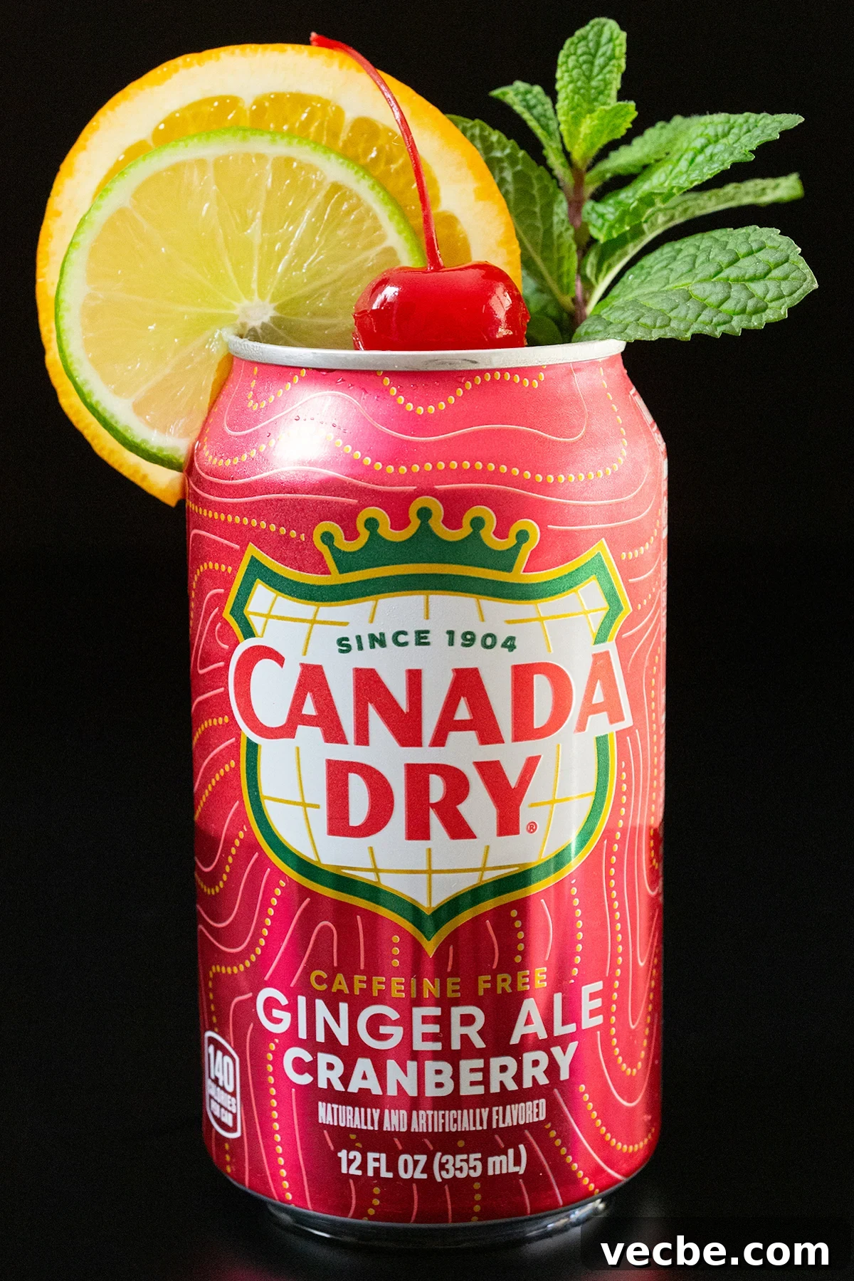 How to Make Canned Christmas Punch 2 A can of cranberry flavored ginger ale has had the top removed and is garnished with a lime wheel, an orange wheel, a sprig of mint, and a maraschino cherry in the middle.