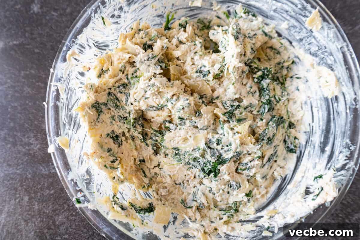 Creamy Hot Artichoke Dip Recipe 7 artichoke dip fully mixed in glass bowl.
