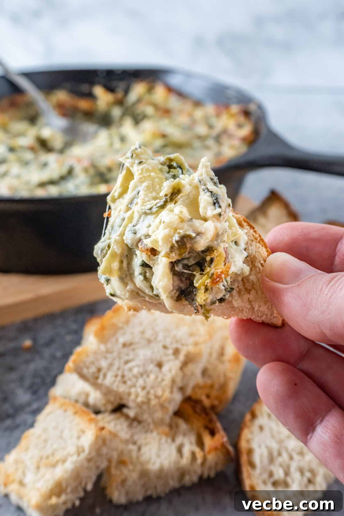 Creamy Hot Artichoke Dip Recipe 9 Hot Spinach Artichoke Dip on Bread being held in hand.