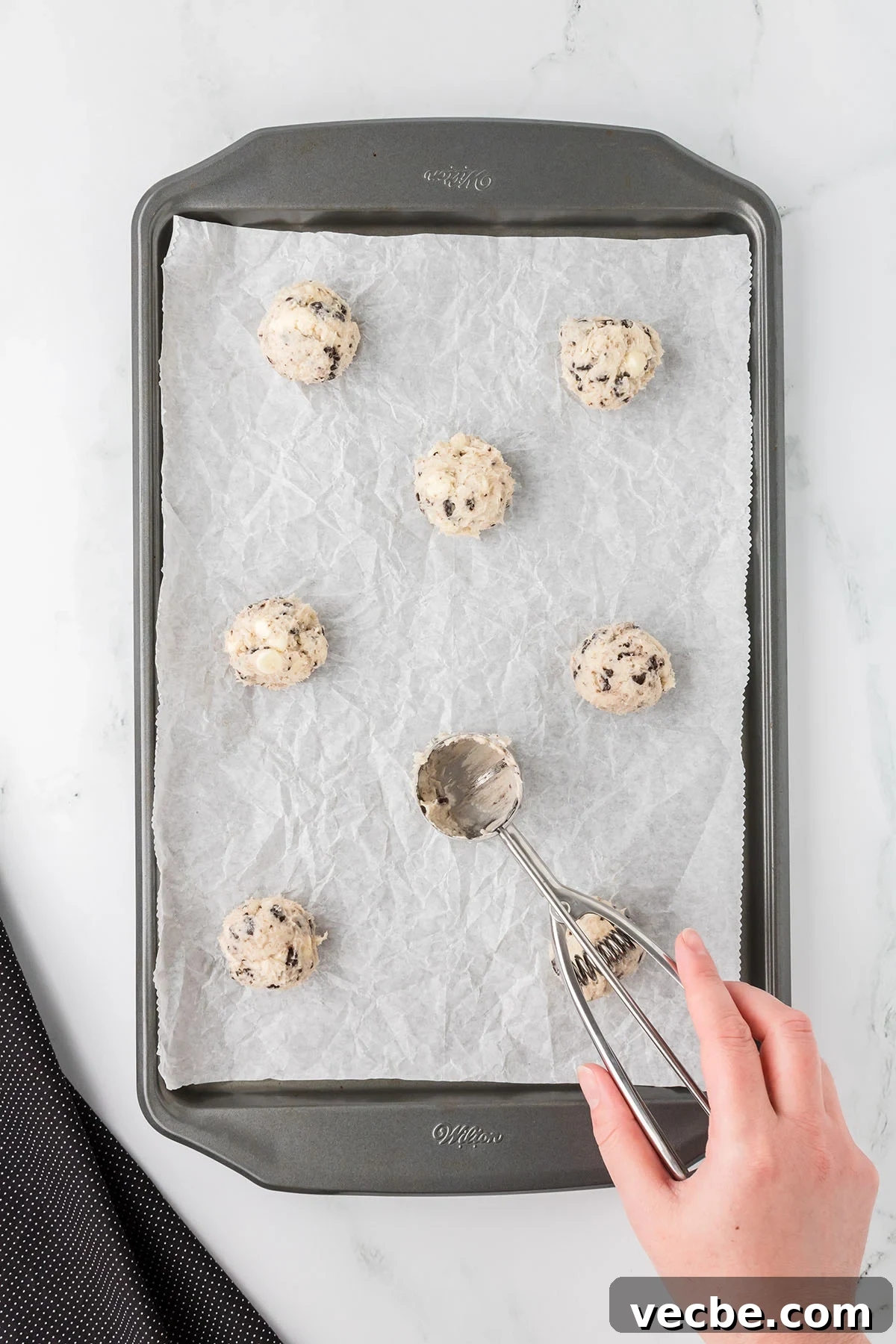 Cookies and Cream Cheesecake Cookie Bites 7 Cookie dough balls placed on a parchment paper lined baking sheet.