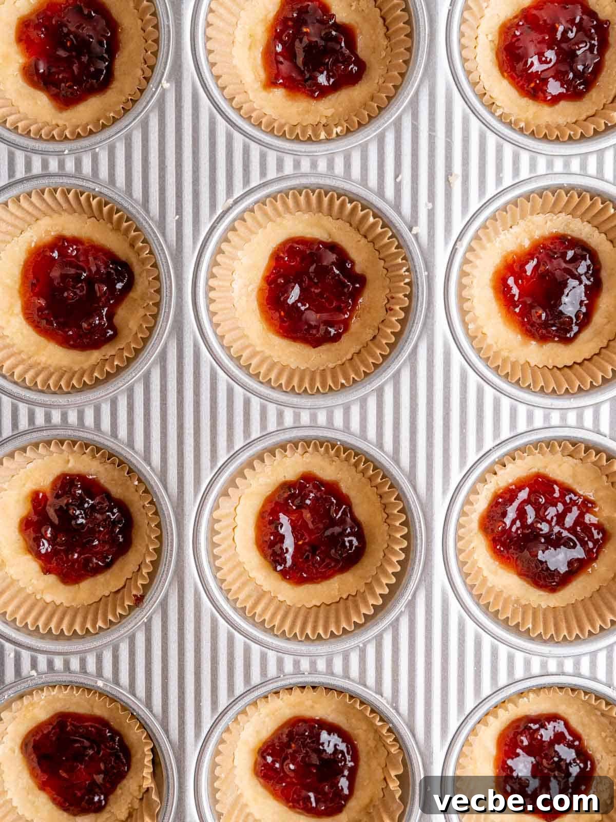 Raspberry Crumble Cookies Better Than Costco 7 Cookie dough in muffin liners with raspberry jam on top.