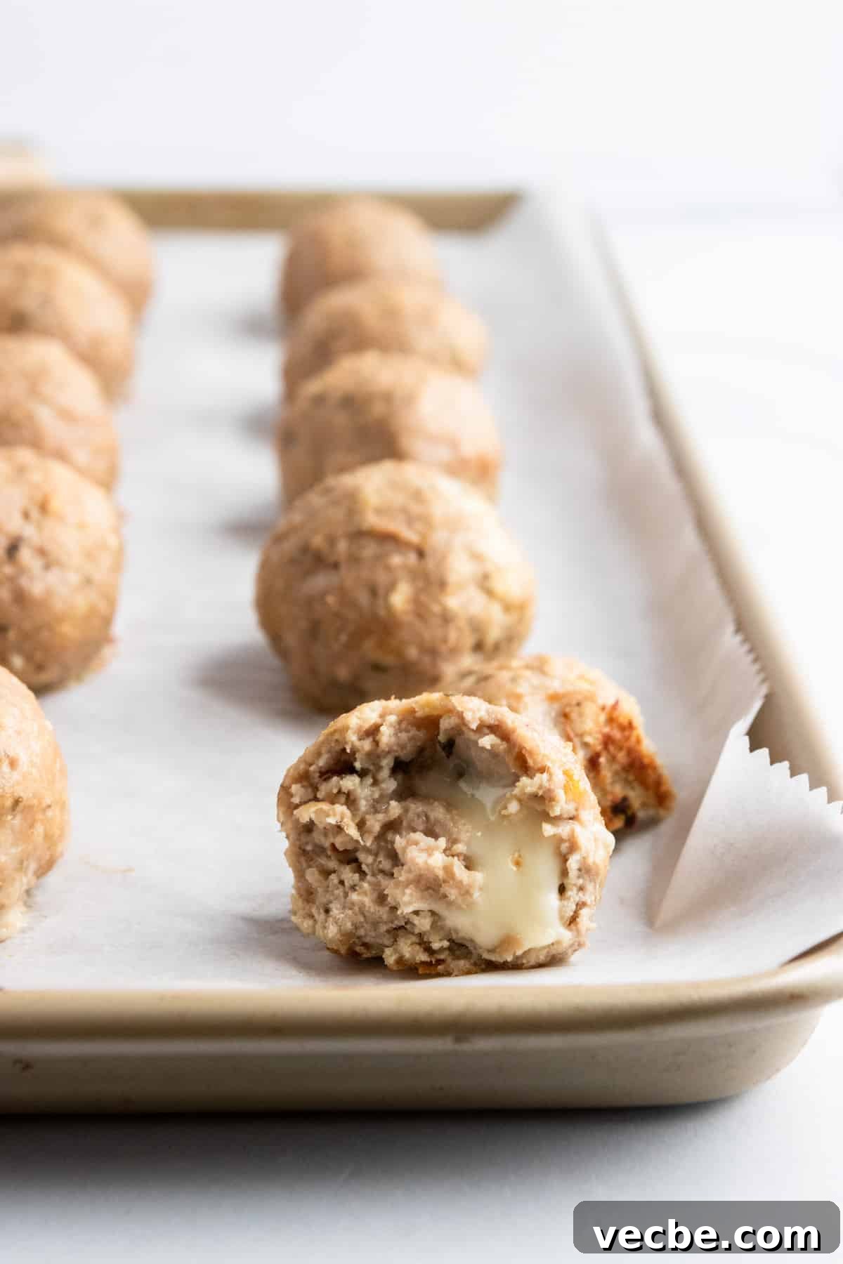 Mozzarella Stuffed Turkey Meatballs Recipe 6 Baked meatballs on baking pan with mozzarella oozing.