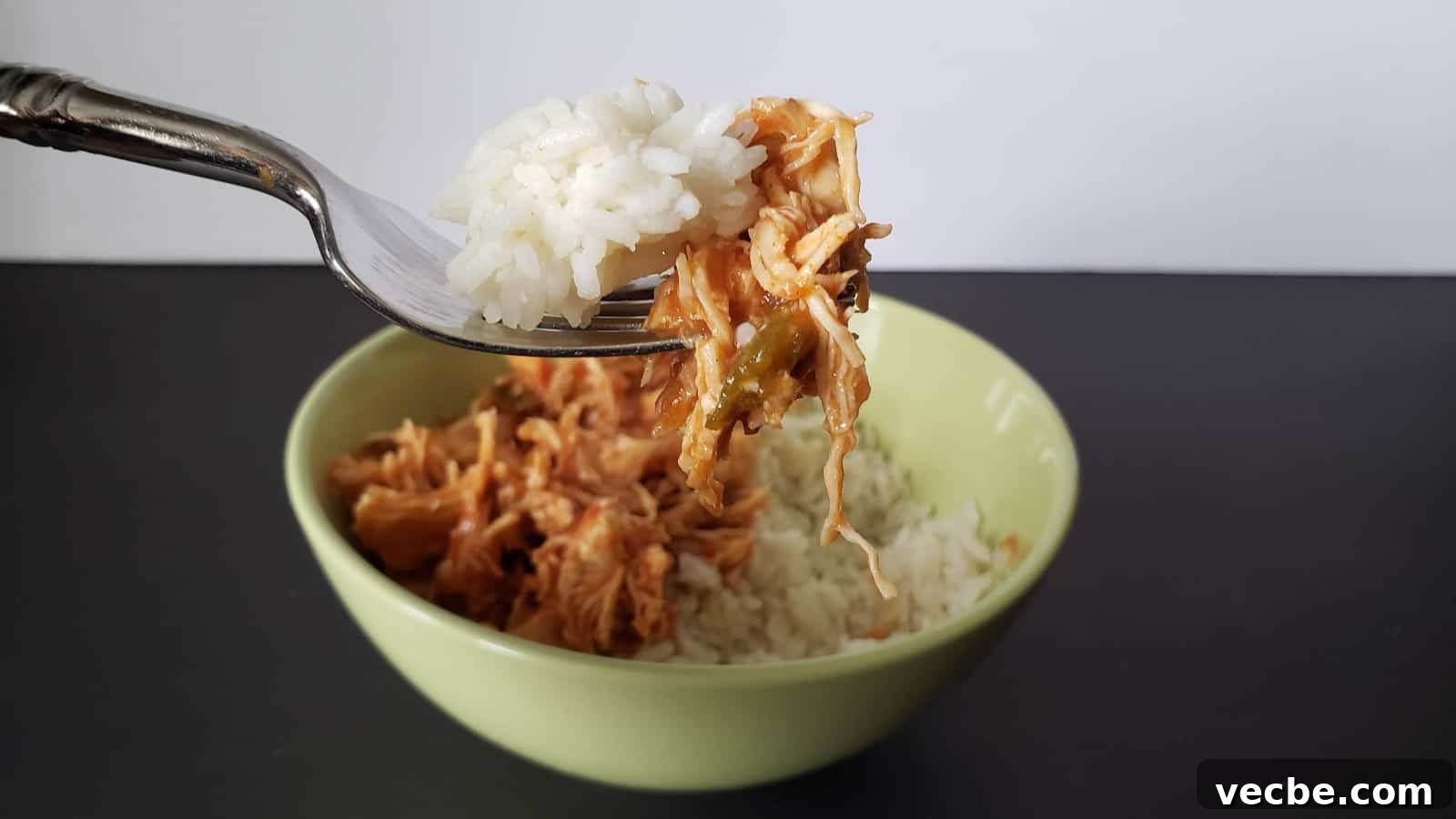 19 Budget-Friendly Meals to Replace Takeout 11 Image shows a Bite of tomato lime chicken on a fork with rice and the rest of the bowl in the background.