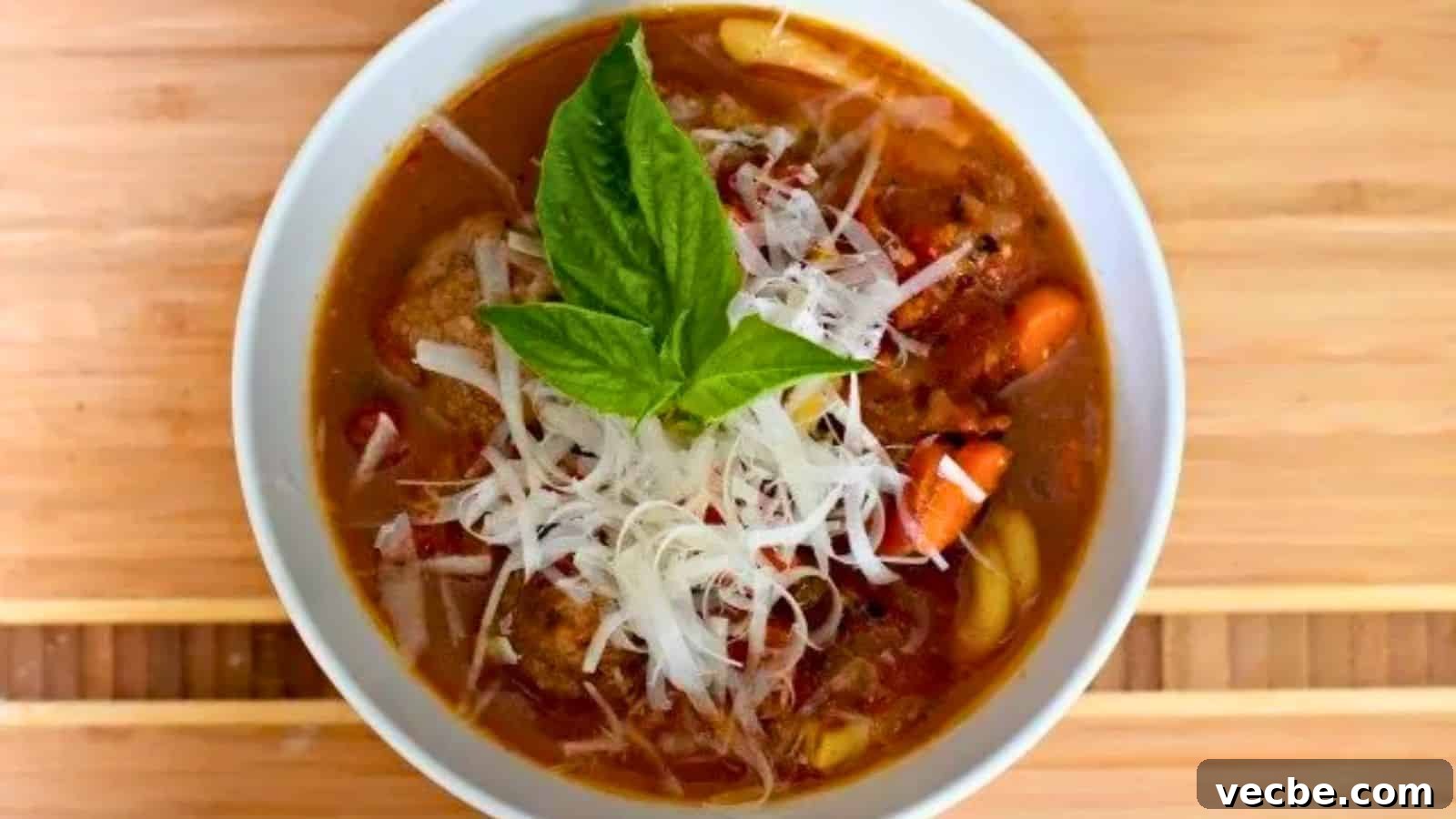 19 Budget-Friendly Meals to Replace Takeout 10 Image shows A bowl of italian meatball soup with a basil leaf on top.