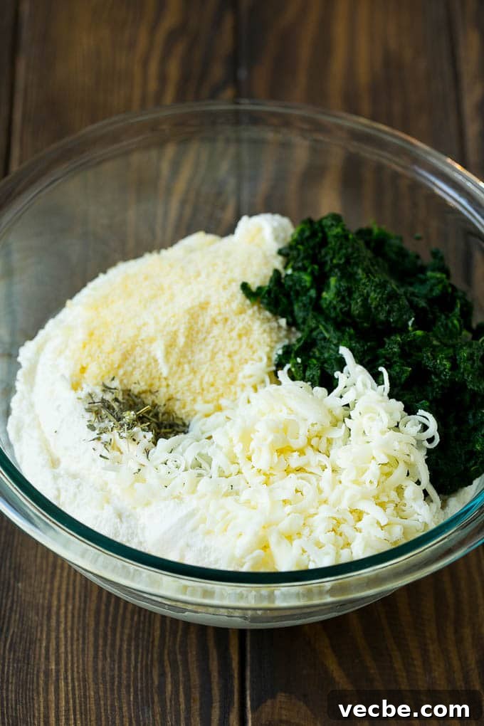 Spinach Lasagna Recipe | Vegetarian Lasagna #lasagna #spinach #cheese #pasta #italianfood #dinner #dinneratthezoo Three types of cheese, seasonings and freshly cooked spinach in a bowl.