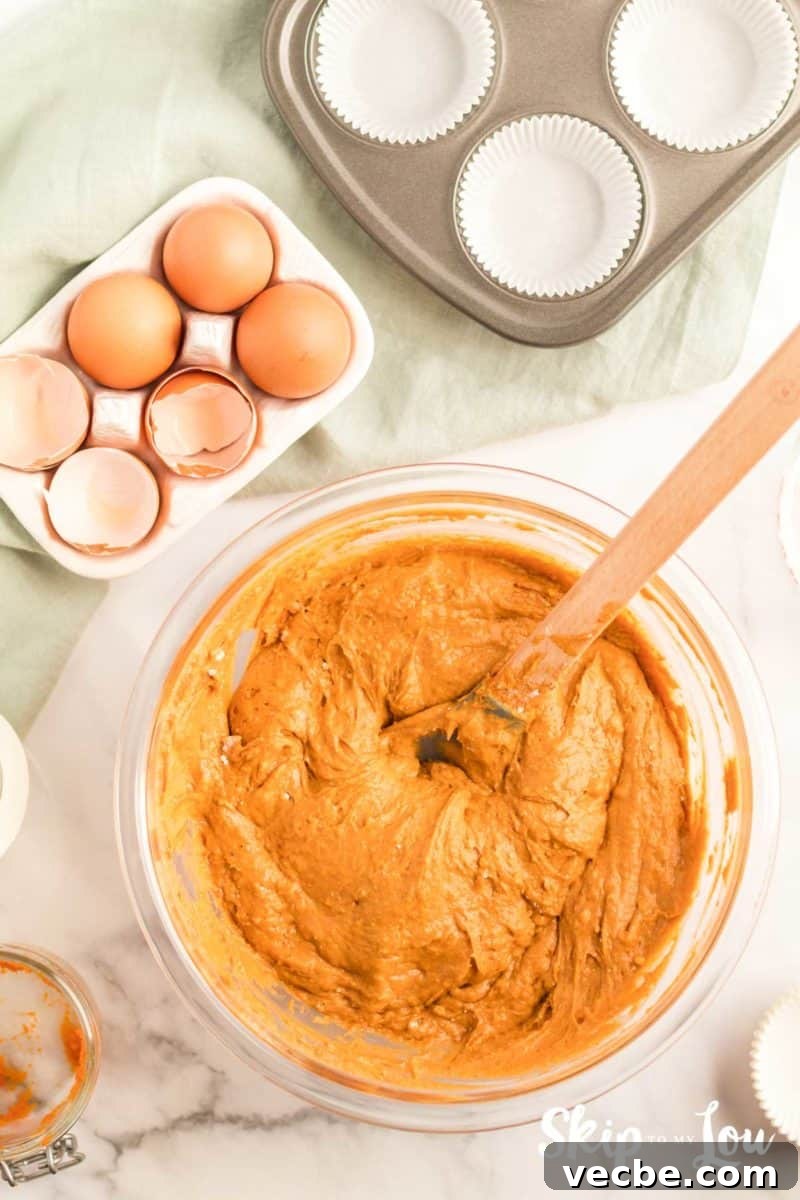 Pumpkin Cake Mix Muffins Recipe 5 pumpkin muffin batter with a wooden spoon used to mix the batter