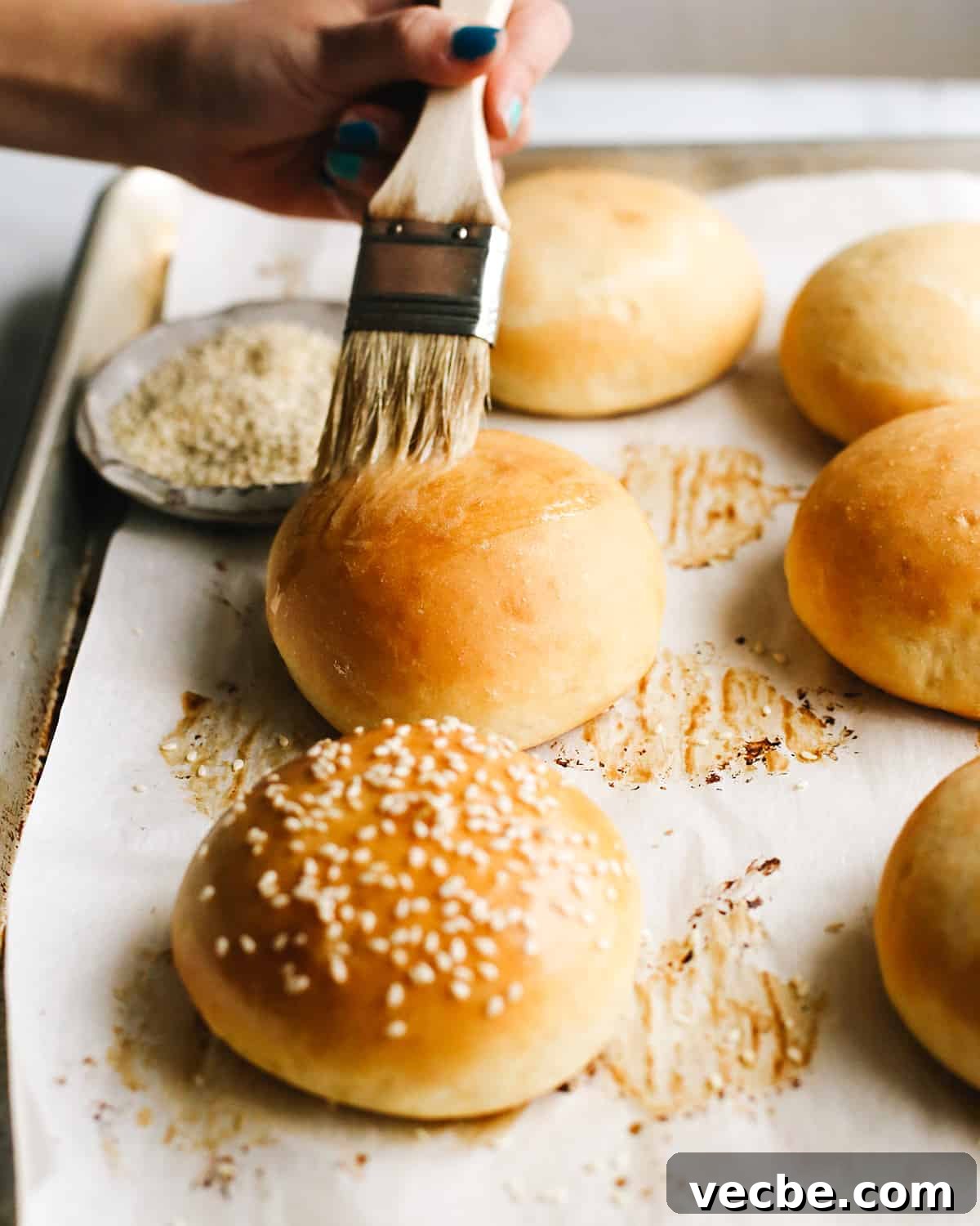 Homemade Hamburger Buns Recipe 4 butter being brushed onto the top of a homemade hamburger bun