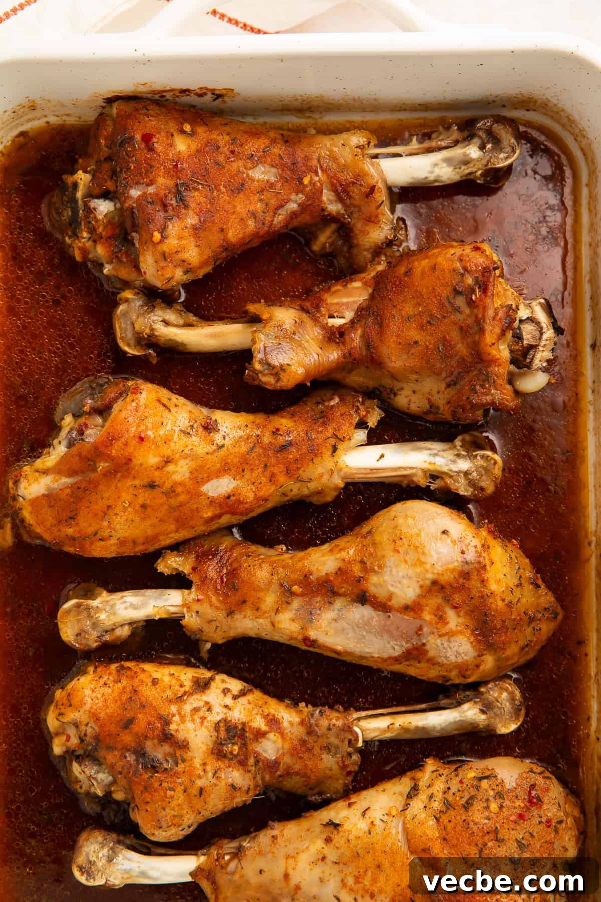 Juicy Oven Roasted Turkey Legs Recipe 2 Six roasted turkey legs sitting in a pan gravy, covered in a spice rub.