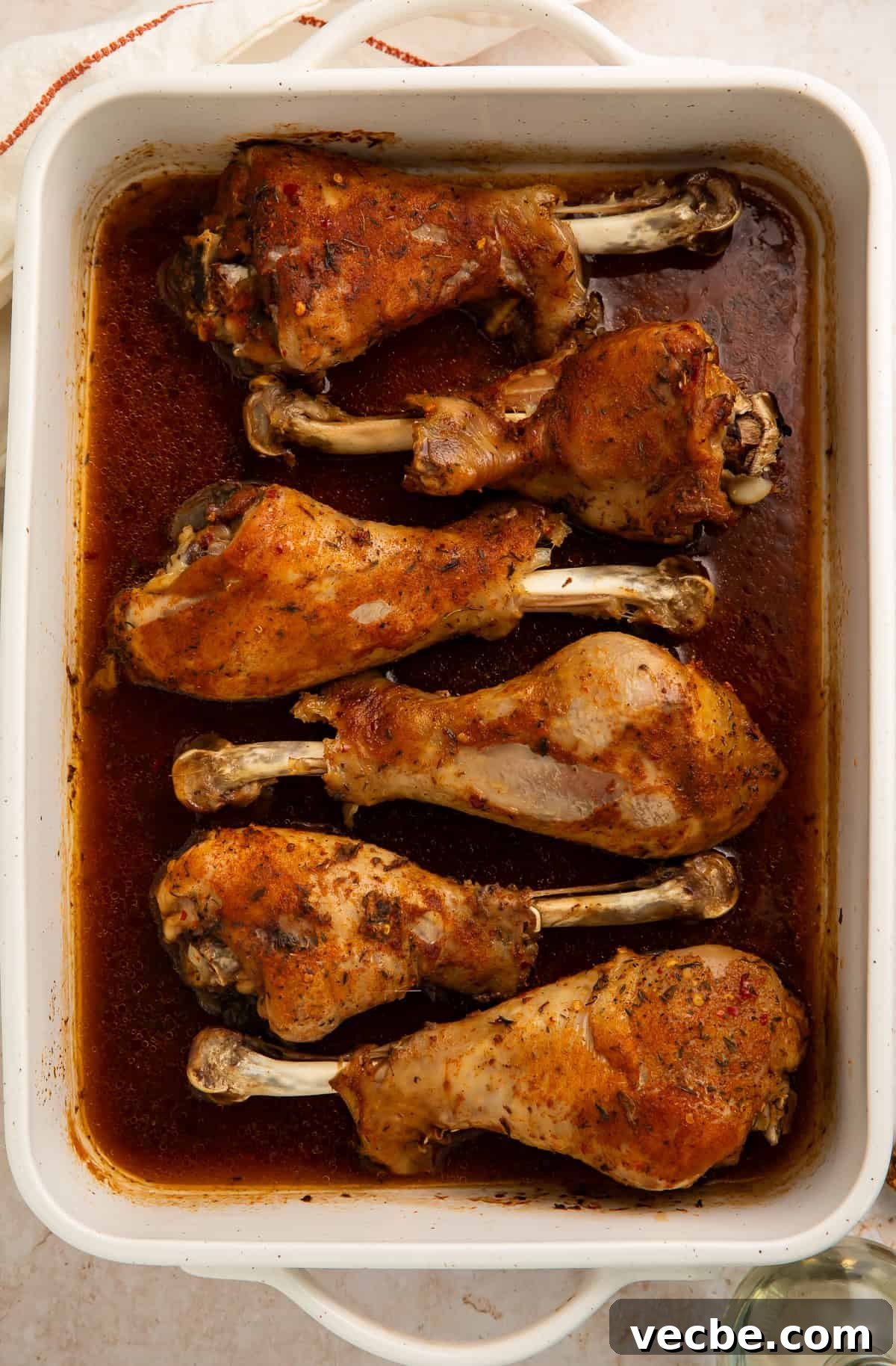 Juicy Oven Roasted Turkey Legs Recipe 3 White baking dish with six turkey legs nestled in a pool of gravy.