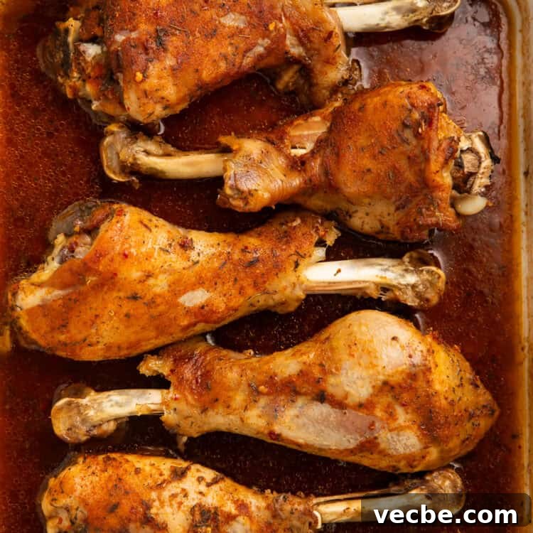 Juicy Oven Roasted Turkey Legs Recipe 5 Six roasted turkey legs sitting in a pan gravy, covered in a spice rub.