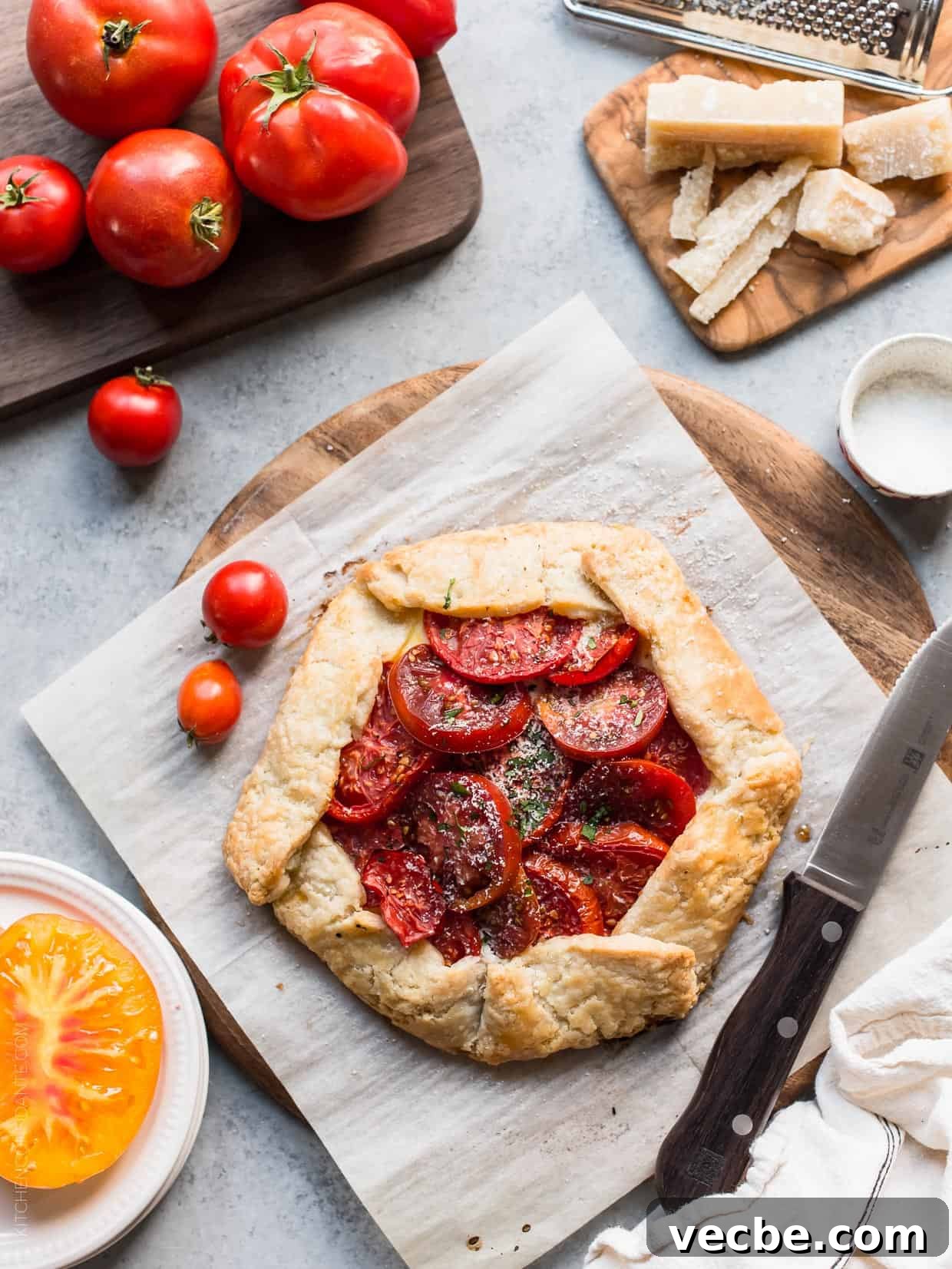 Rustic Tomato and Ricotta Galette Recipe 2 Tomato Galette surrounded by fresh heirloom tomatoes and Parmesan cheese.
