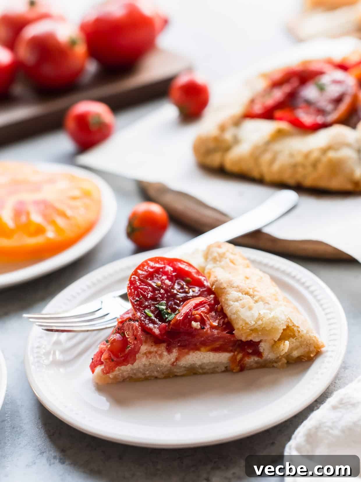 Rustic Tomato and Ricotta Galette Recipe 8 A slice of Tomato Ricotta Galette on a white plate with a fork.