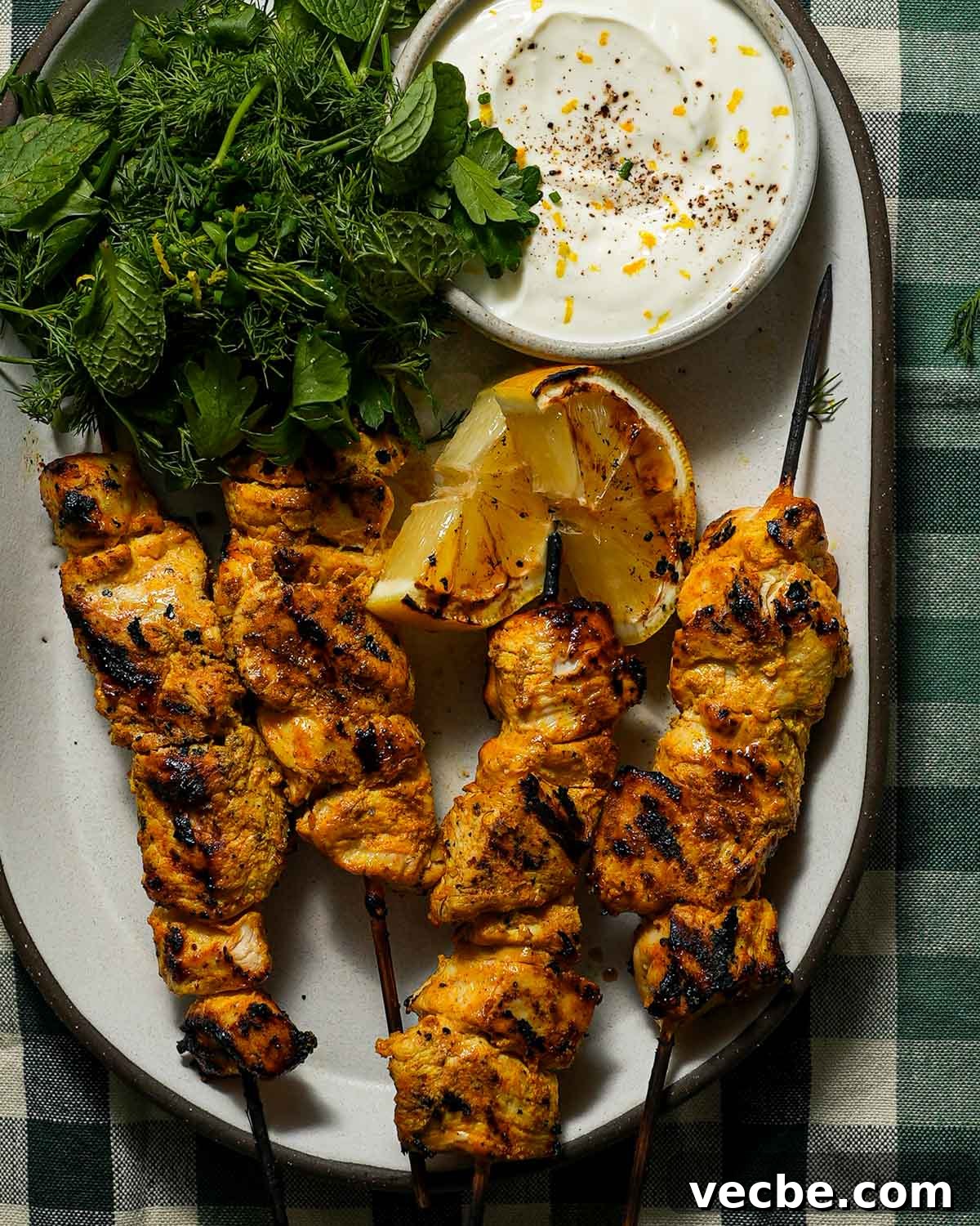 Yogurt-Marinated Grilled Chicken Skewers Recipe 2 A platter of grilled yogurt marinated chicken with a charred lemon, yogurt and herbs.