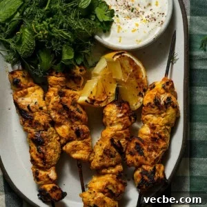 Yogurt-Marinated Grilled Chicken Skewers Recipe 12 A platter of grilled yogurt marinated chicken with a charred lemon, yogurt and herbs.