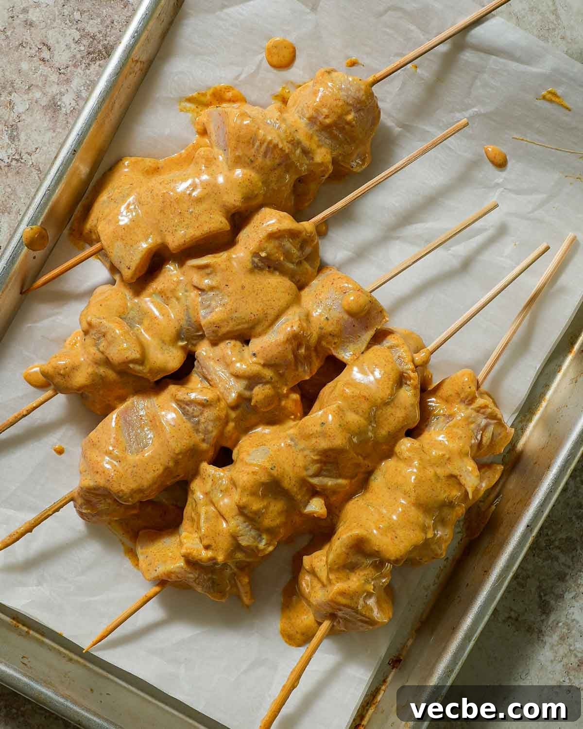 Yogurt-Marinated Grilled Chicken Skewers Recipe 5 Yogurt marinated skewers on baking sheet with parchment paper.