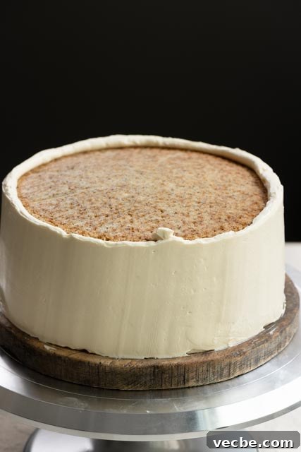Moist Banana Layer Cake with Honey Buttercream Recipe 14 Partially frosted two layer cake with honey buttercream on a turntable.