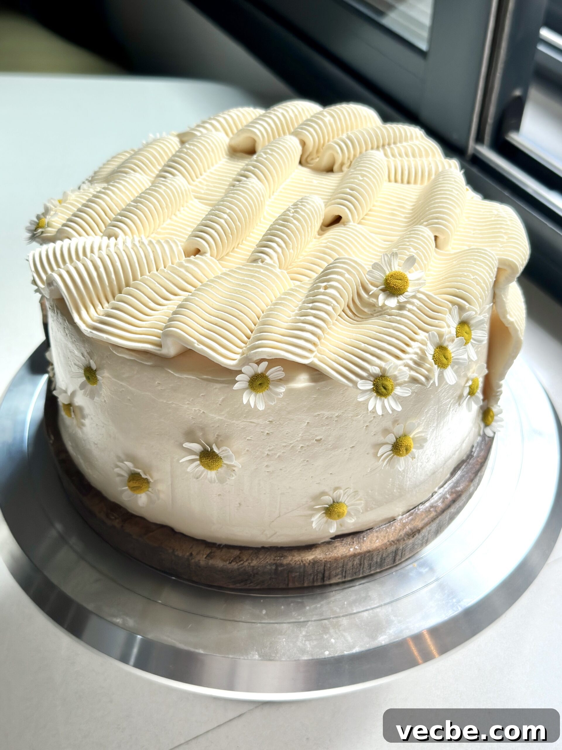 Moist Banana Layer Cake with Honey Buttercream Recipe 15 Frosted two layer banana cake with rippled frosting and edible flowers.