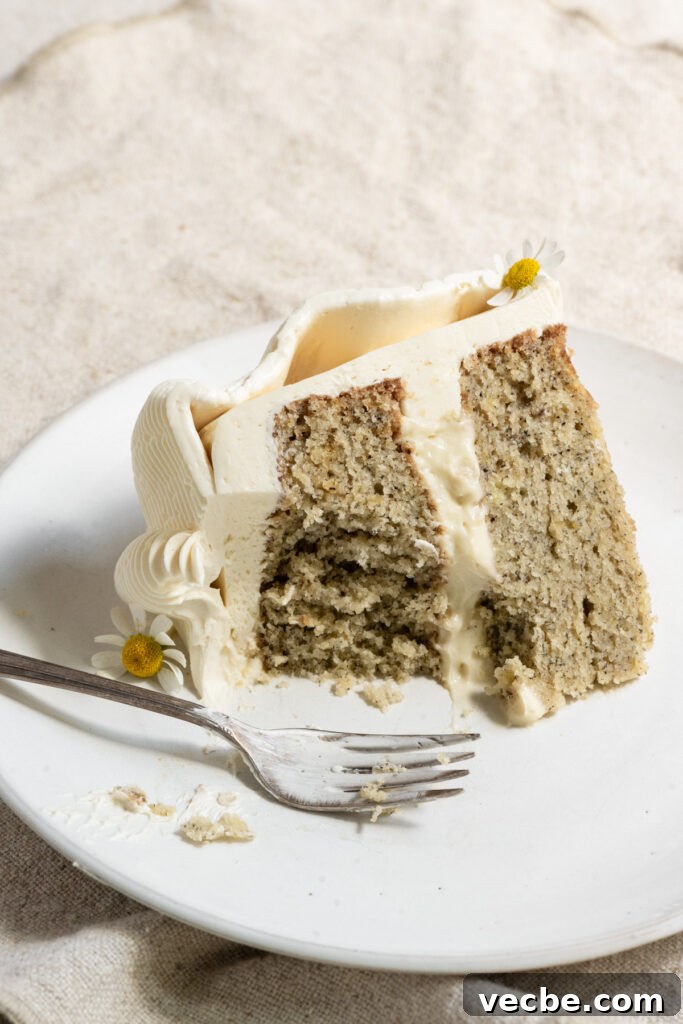 Moist Banana Layer Cake with Honey Buttercream Recipe 16 Slice of banana layer cake partially eaten on a plate with a fork.
