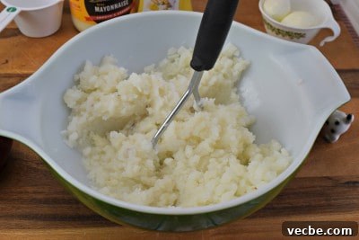 Creamy Mashed Potato Salad Recipe 6 Mash potatoes with a potato masher.