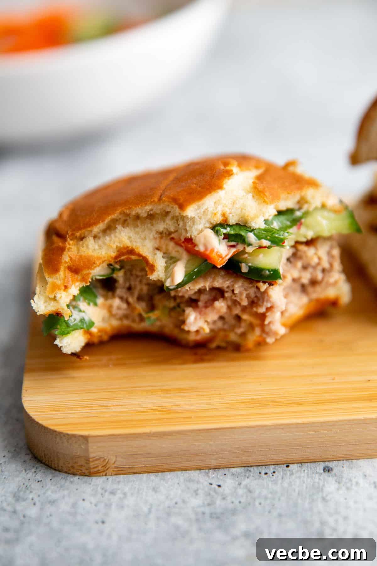 Banh Mi Burger Recipe with Sriracha Cream Cheese 10 a half eaten burger sitting on a cutting board