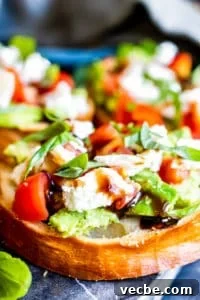 Caprese Avocado Toast Close Up Close up shot of avocado toast on a blue cutting board.