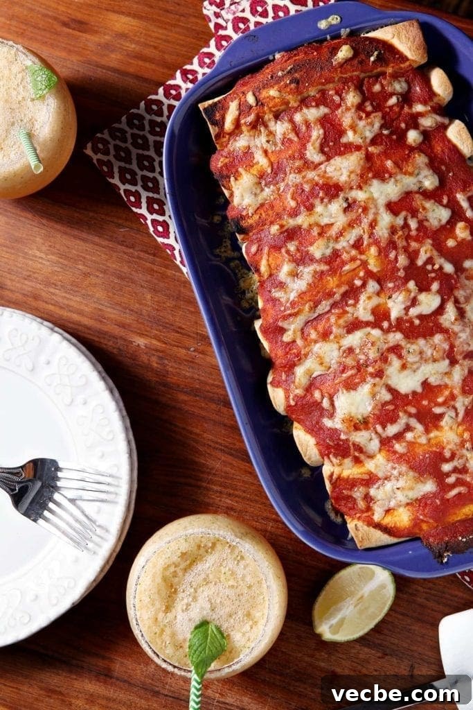 Pork Carnitas Enchiladas with Salsa Verde 5 Overhead shot of a baking dish full of baked enchiladas, surrounded by plates and margaritas, on a wooden background