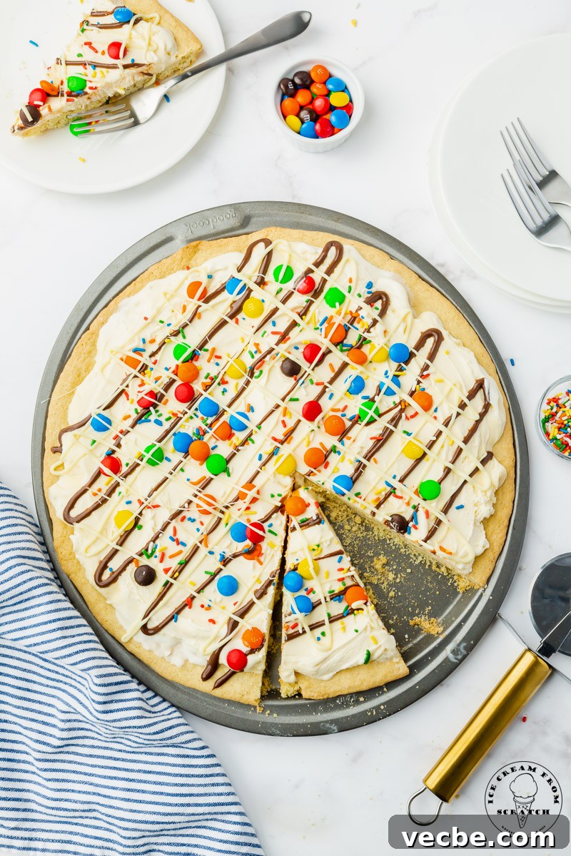 No-Bake Ice Cream Pizza Recipe with Cookie Crust 5 a large round cookie topped with ice cream to create an ice cream pizza with candy, sprinkles, and chocolate toppings.