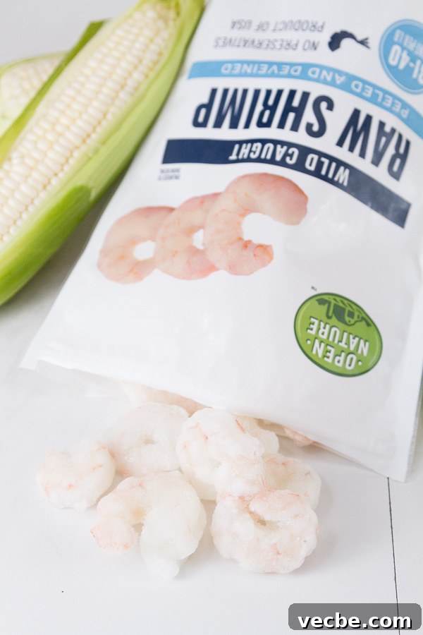 Caribbean Shrimp Foil Packets with Pineapple and Peppers 4 A bag of Open Nature Raw Shrimp open and the shrimp coming out of it with an ear of corn in the background