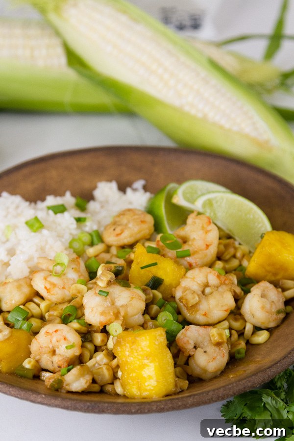Caribbean Shrimp Foil Packets with Pineapple and Peppers 5 Foil Packet Caribbean Shrimp served with coconut rice on a brown bowl with ears of corn in the background