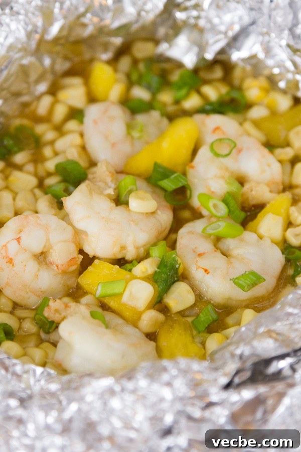Caribbean Shrimp Foil Packets with Pineapple and Peppers 7 close up on an open Foil Packet of Caribbean Shrimp with shrimp, corn, pineapple, and green onions
