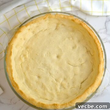 Gluten-Free Coconut Flour Pie Crust Recipe 9 A coconut flour pie crust in a glass dish on a marble countertop.