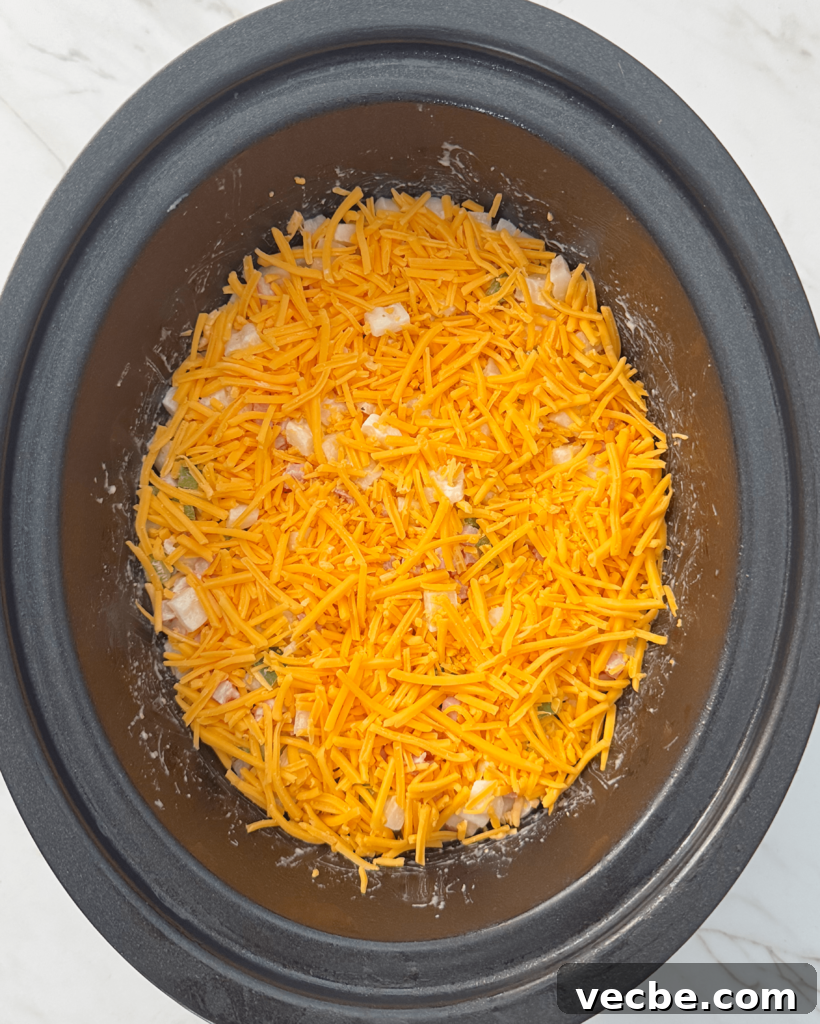overhead shot of uncooked Cheesy Breakfast Potatoes in a black slow cooker