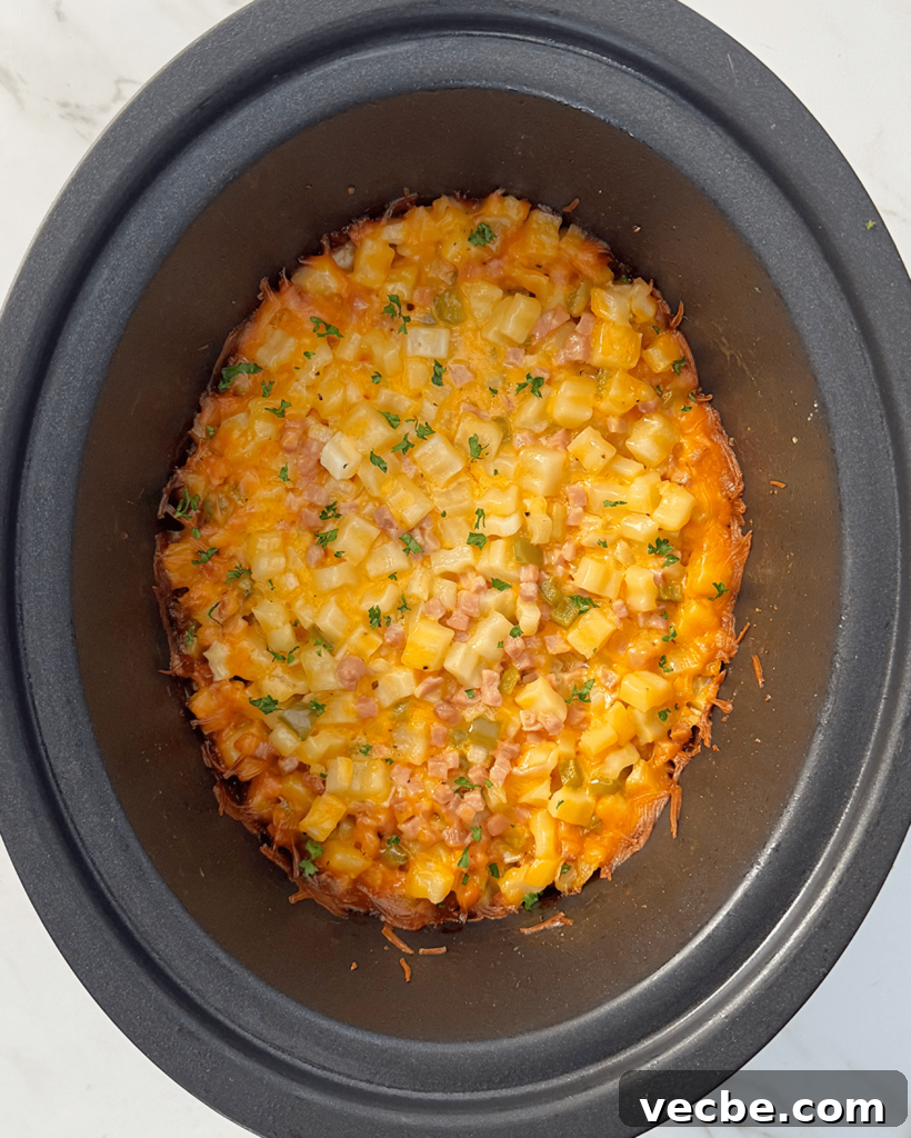 overhead shot of cooked Cheesy Breakfast Potatoes in a black slow cooker