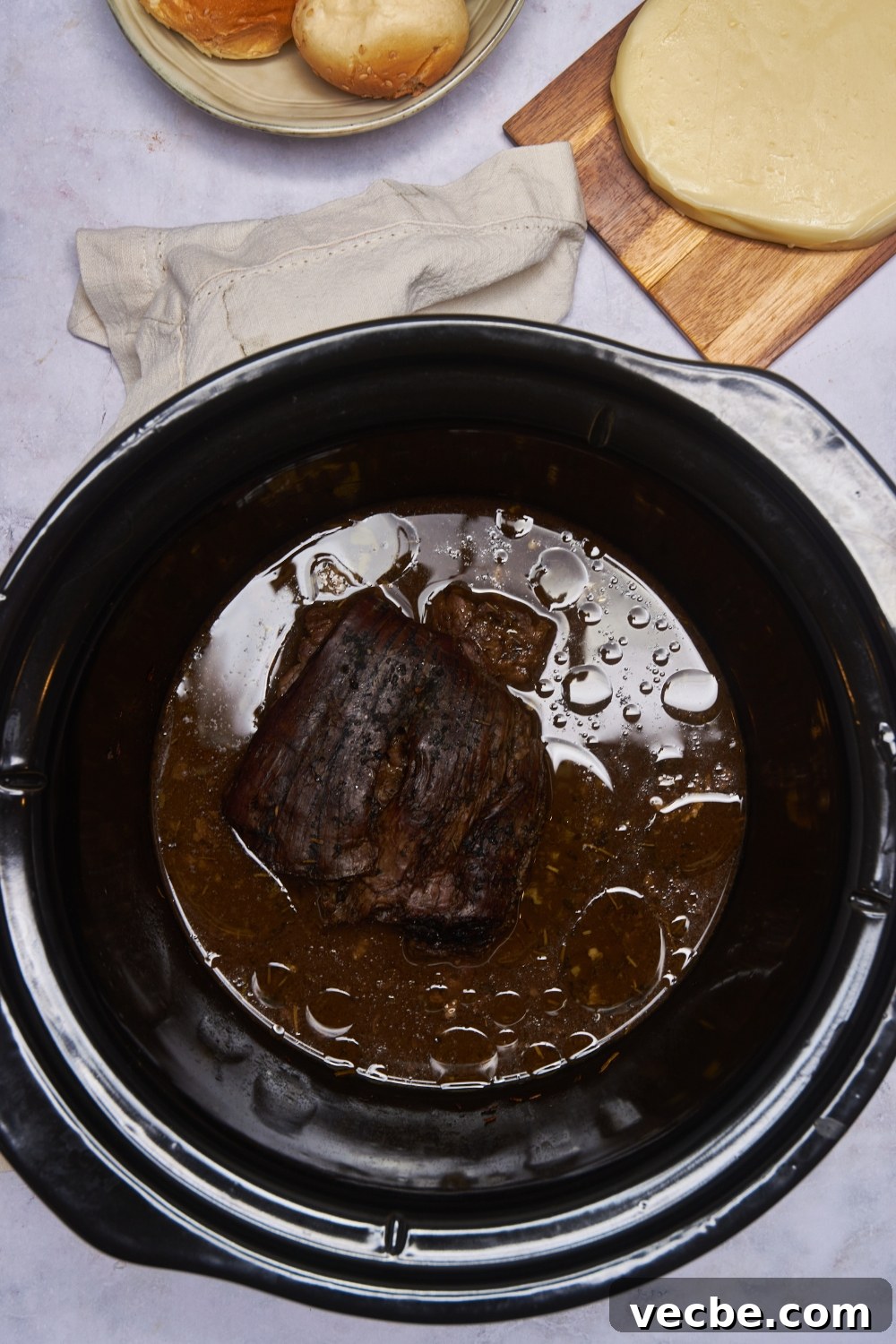 Fall-Apart Slow Cooker Tri-Tip Recipe 7 A black crockpot filled with cooked tri tip in a brown gravy.