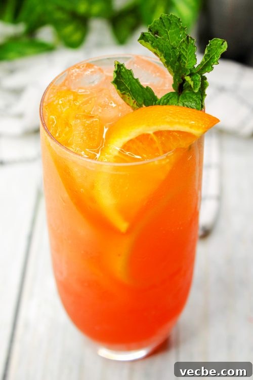 Azalea Cocktail Recipe with Vodka and Pineapple Juice 2 a coral colored Azalea Cocktail garnished with an orange slice and mint.