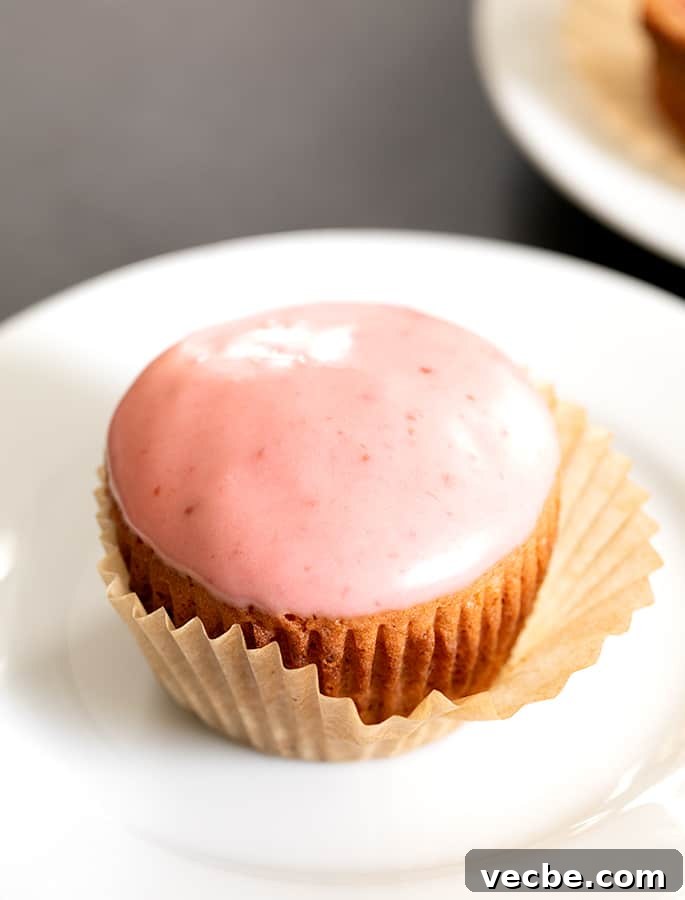 Homemade Strawberry Puree and Syrup Recipe 7 Strawberry cupcake on a plate with the liner peeling off.