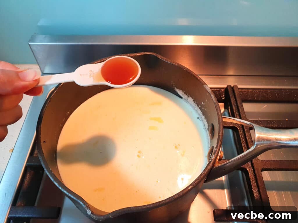 Cookies and Cream Ice Cream Recipe 11 adding vanilla to ice cream mix in pot on stove.