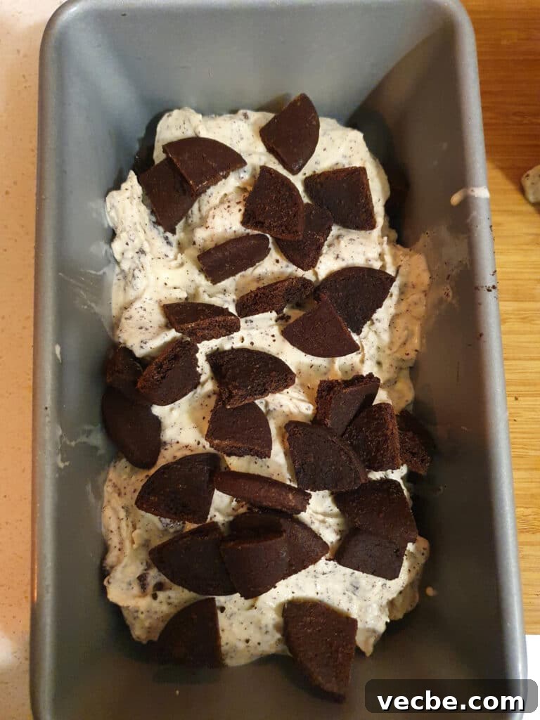Cookies and Cream Ice Cream Recipe 19 adding second layer of cookies to ice cream, about 4 to five cookies that have been cut into quarters.