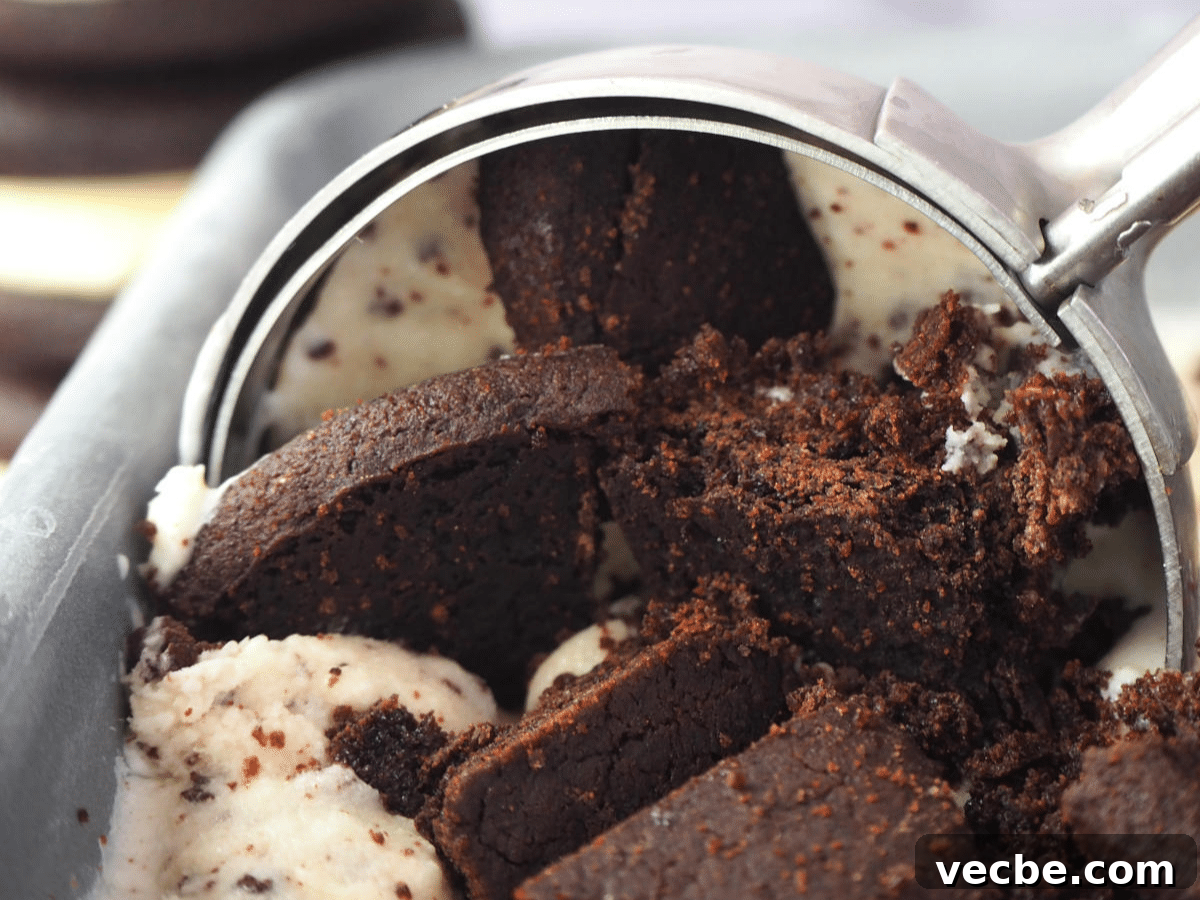 Cookies and Cream Ice Cream Recipe 20 Close up scooping cookies and cream ice cream in loaf pan, with Oreos in the background.