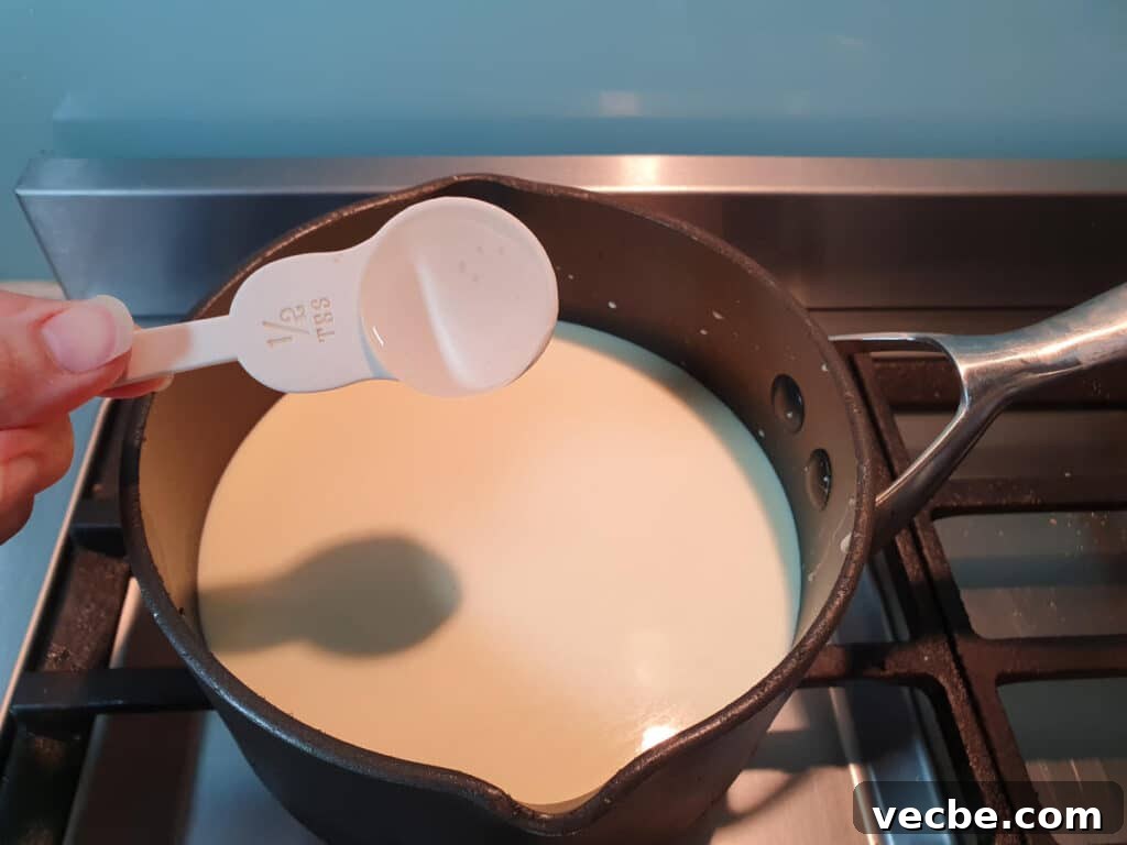 Cookies and Cream Ice Cream Recipe 9 adding glycose syrup to ice cream mix in pot on stove.